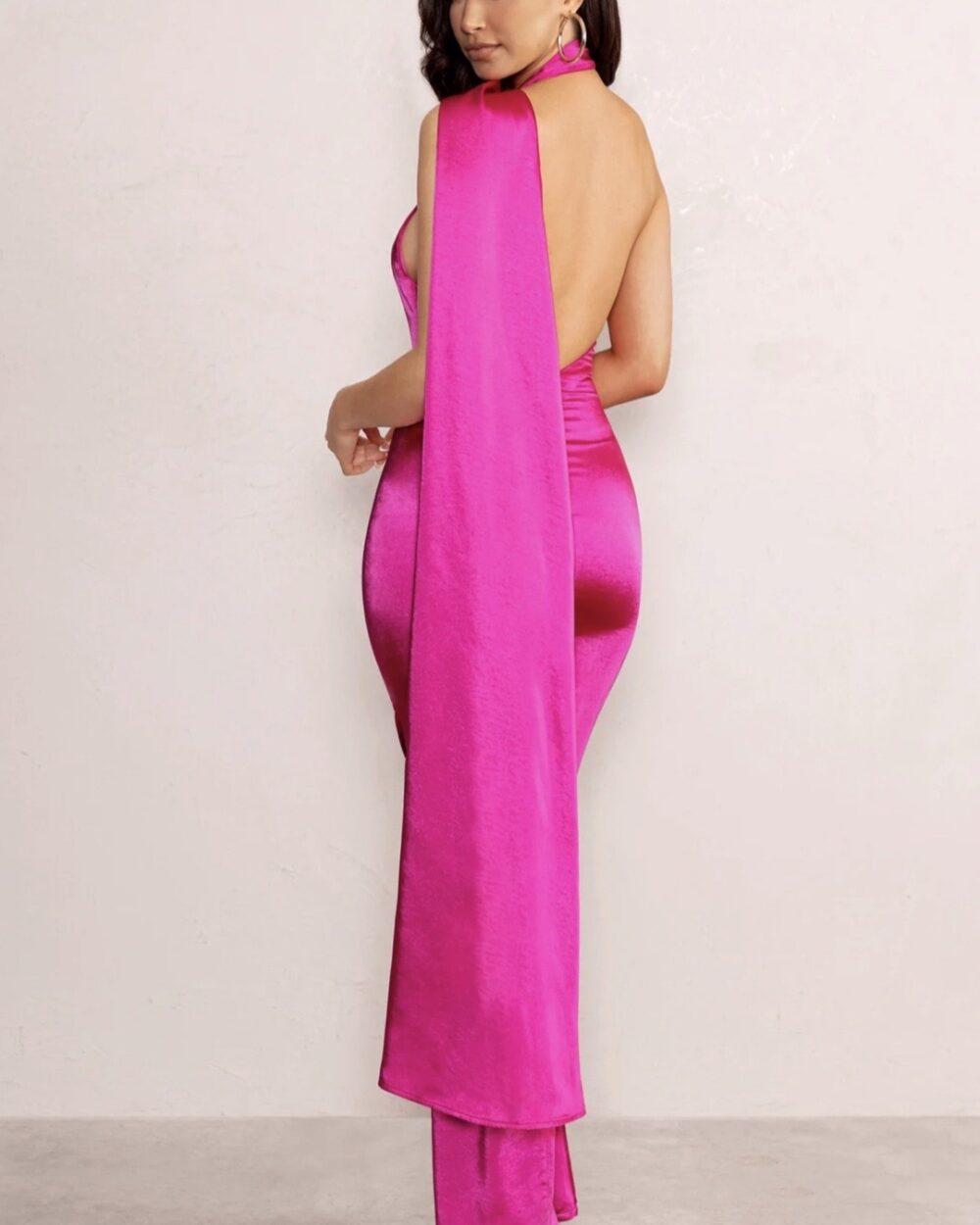 Brunette in hot pink maxi dress with open back looking over her shoulder.